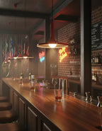Suspension industrielle rouge en métal avec lumière chaude, luminaire parfait pour bar et espace contemporain.